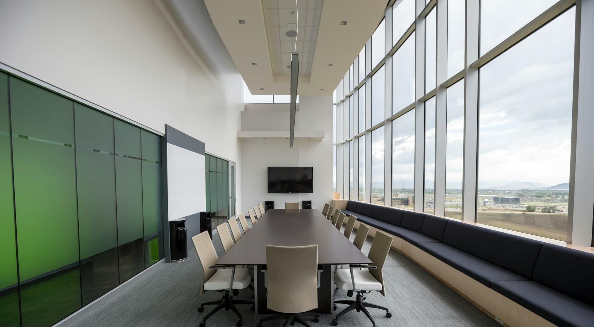 A long conference table in an empty meeting room with floor-to-ceiling windows
