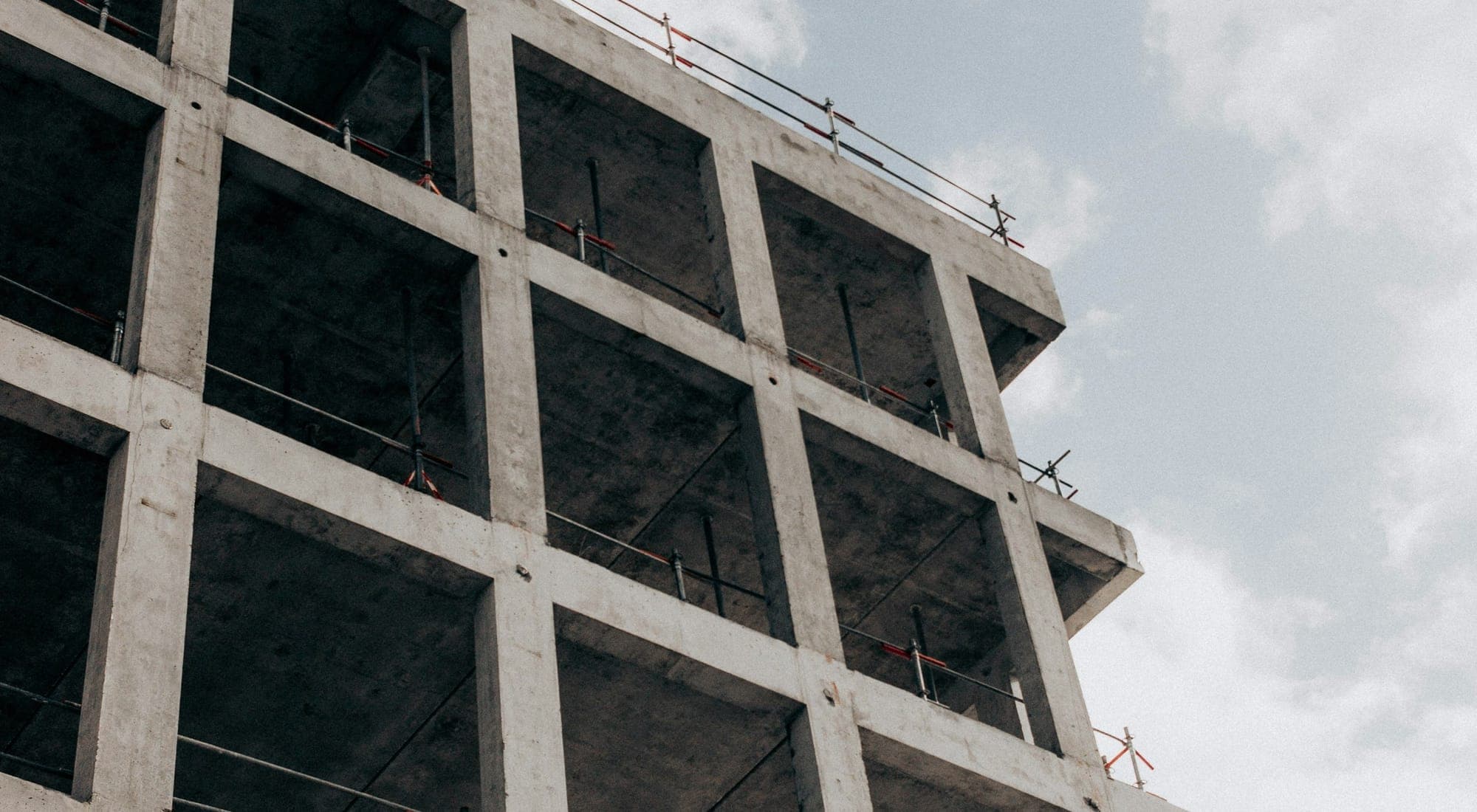 The exposed concrete frame of a building under construction against the sky
